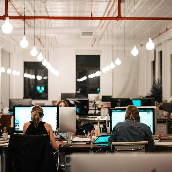 A large open office with a high ceiling and staff seated working on computers.