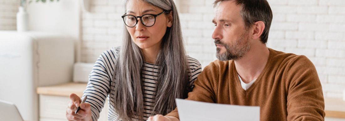 Mature middle-aged couple family wife and husband counting funds and reviewing debt