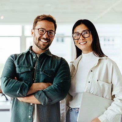 A man and woman in an office smiling at the camera.