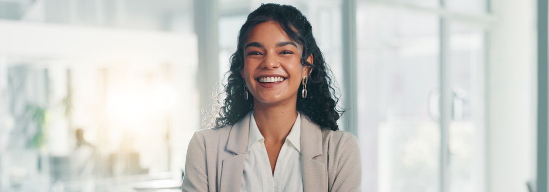 A young woman with long dark curly hair looking at the camera and smiling