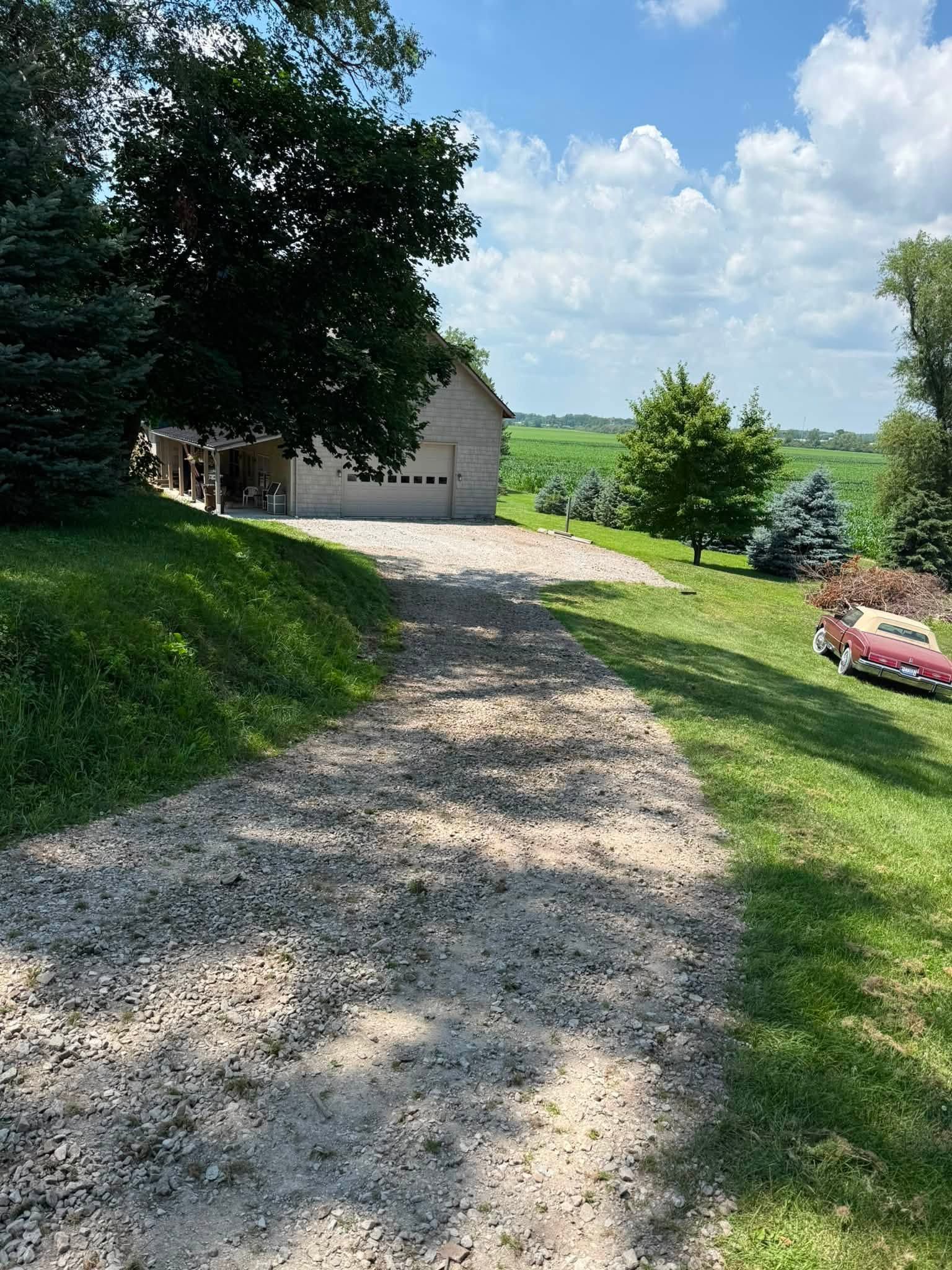 Gravel path beside a stone building and green lawn under a blue sky with clouds