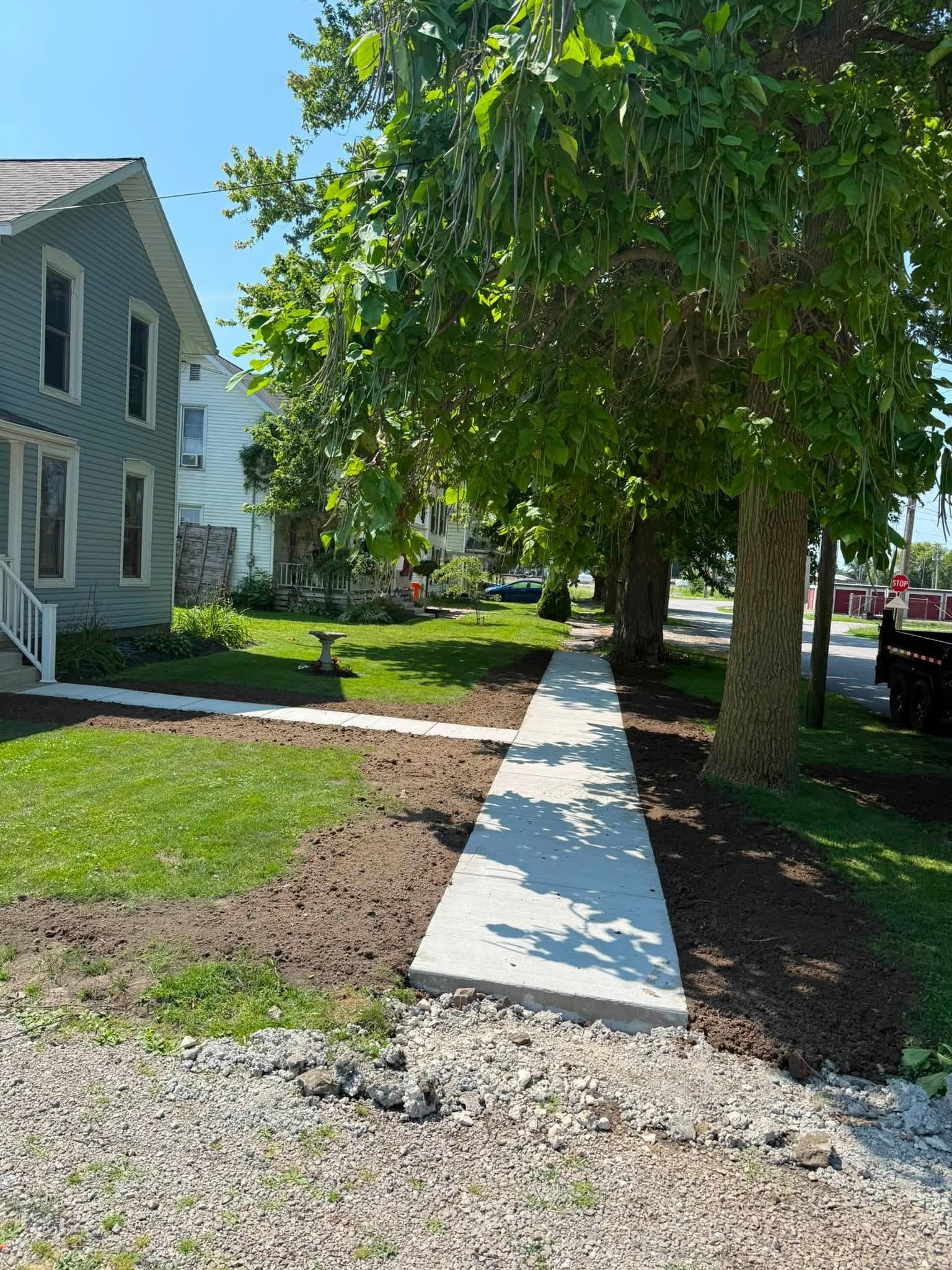 Sidewalk beside houses and trees on a sunny residential street