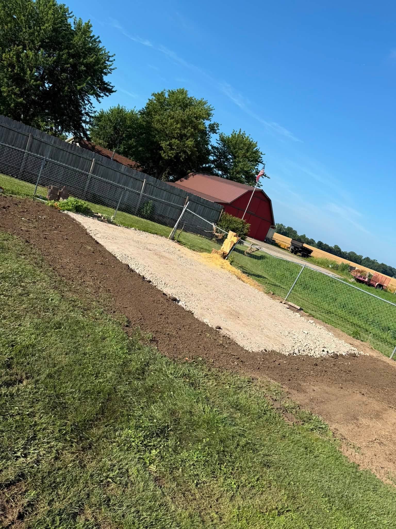 Grassy field with a tan dirt mound, black fence, yellow fire hydrant, and a red barn under a blue sky