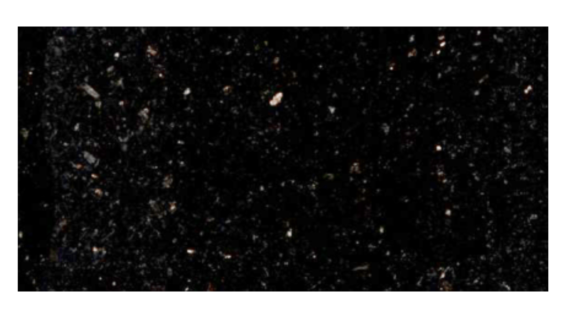 A dark, textured surface resembling black granite with small, reflective white and silver flecks throughout.