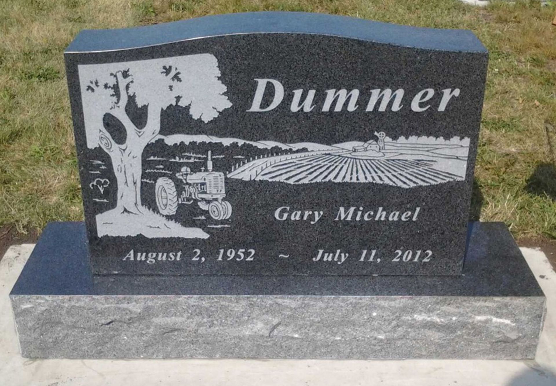 Monument with a colorful landscape scene, black base, and a gray textured lower base.