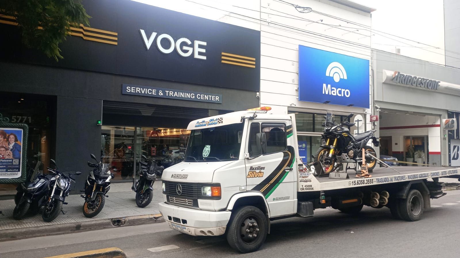 Motocicleta roja atada a una grúa de plataforma en una calle de la ciudad.