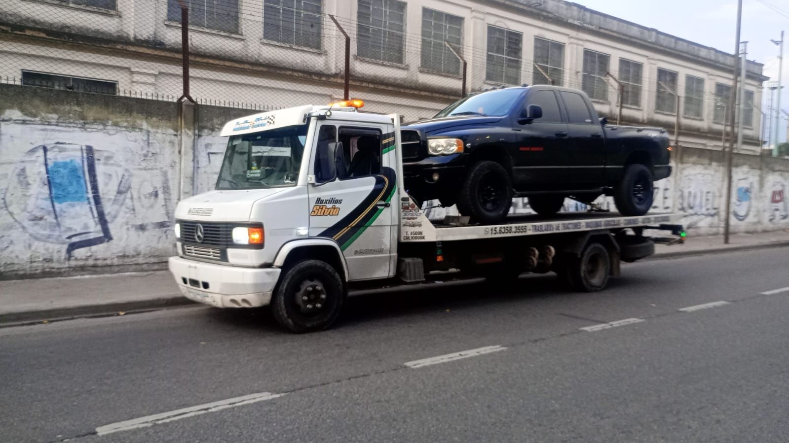 Camioneta azul sobre un remolque para autos en un estacionamiento.
