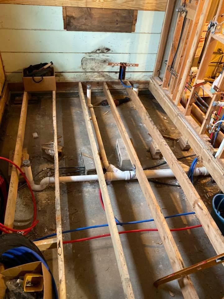 A bathroom under construction with wooden beams and pipes.