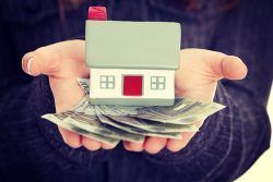 Beautiful,Young,Businesswoman,Holding,Euros,Bills,And,House,Model,Over