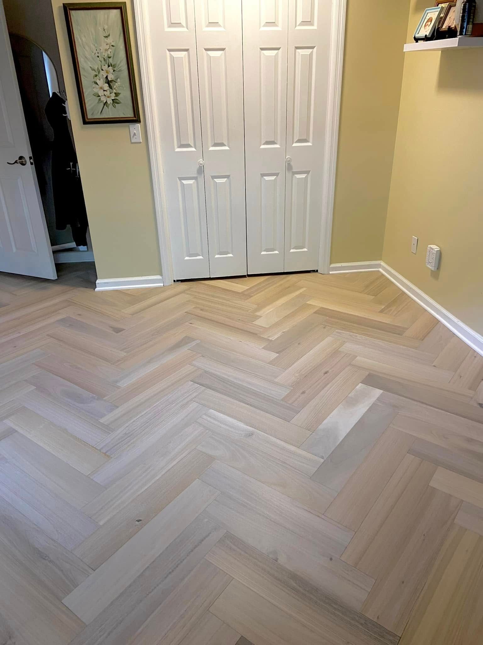 A room with a herringbone wooden floor and white doors.
