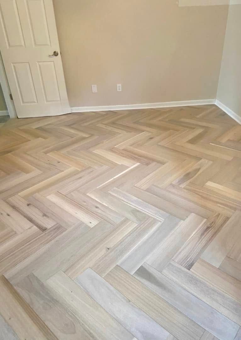 A room with a herringbone floor and a door.