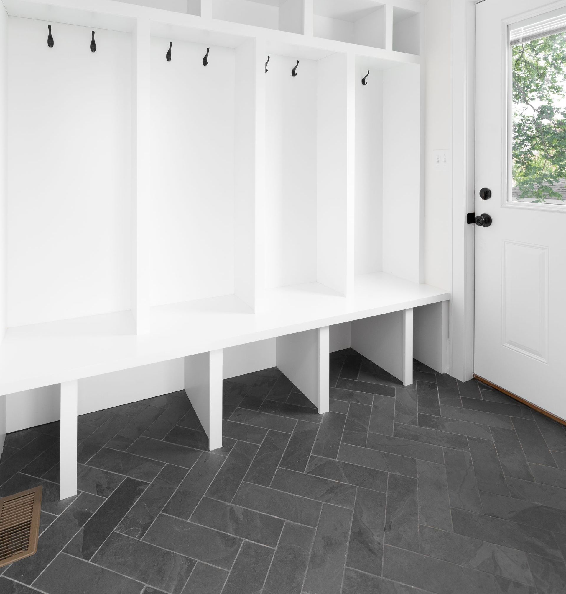 A locker room with a black tile floor and white shelves