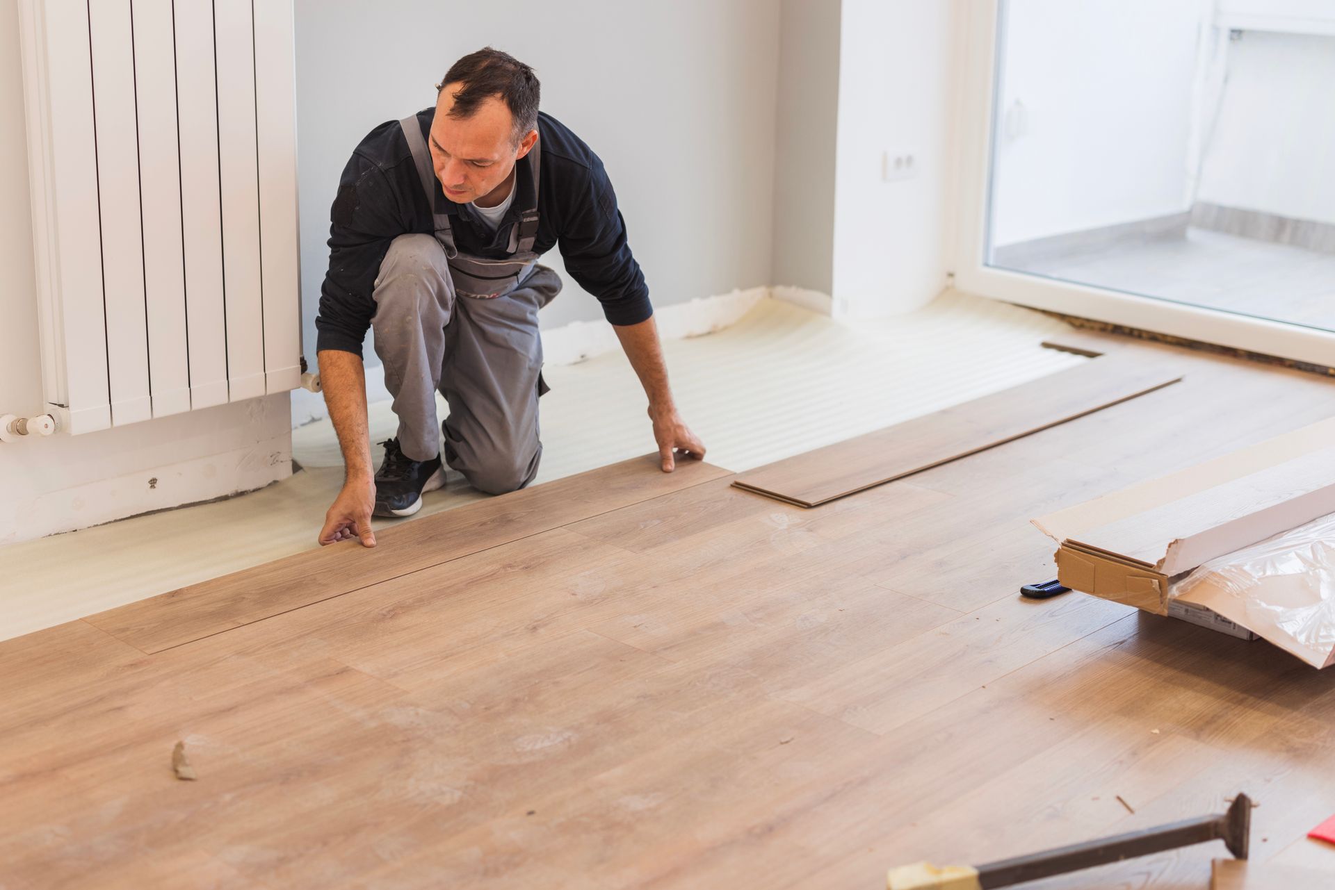 A man is installing a wooden floor in a room.