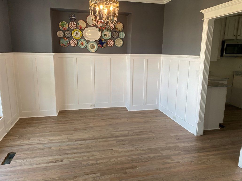 An empty dining room with a chandelier and plates on the wall.