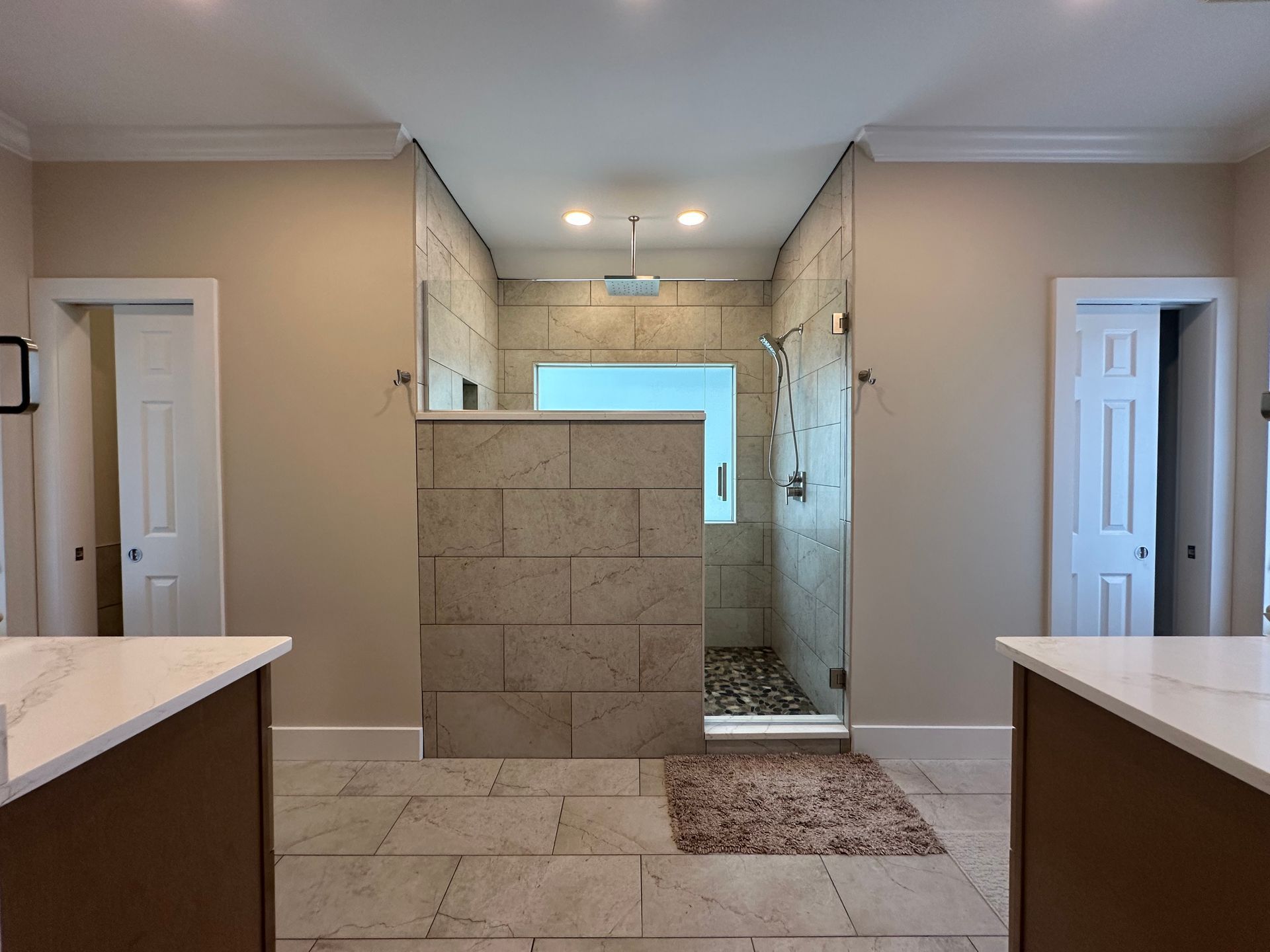 A bathroom with a walk in shower and two sinks