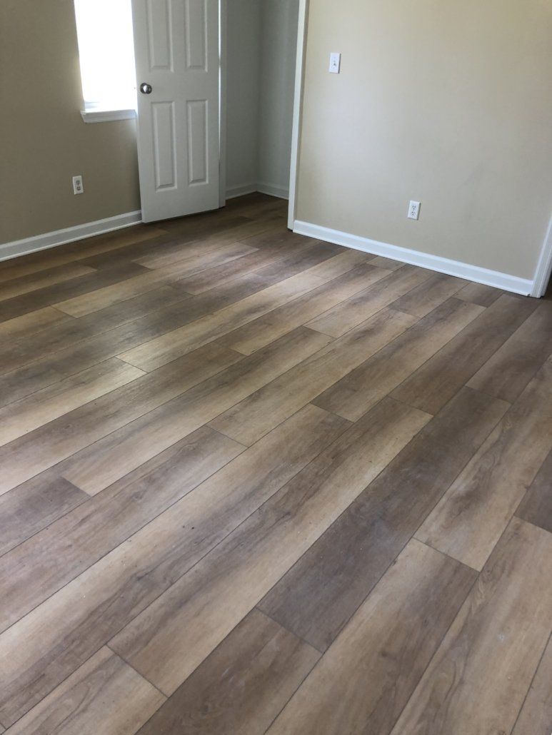 A bedroom with a wooden floor and a window.