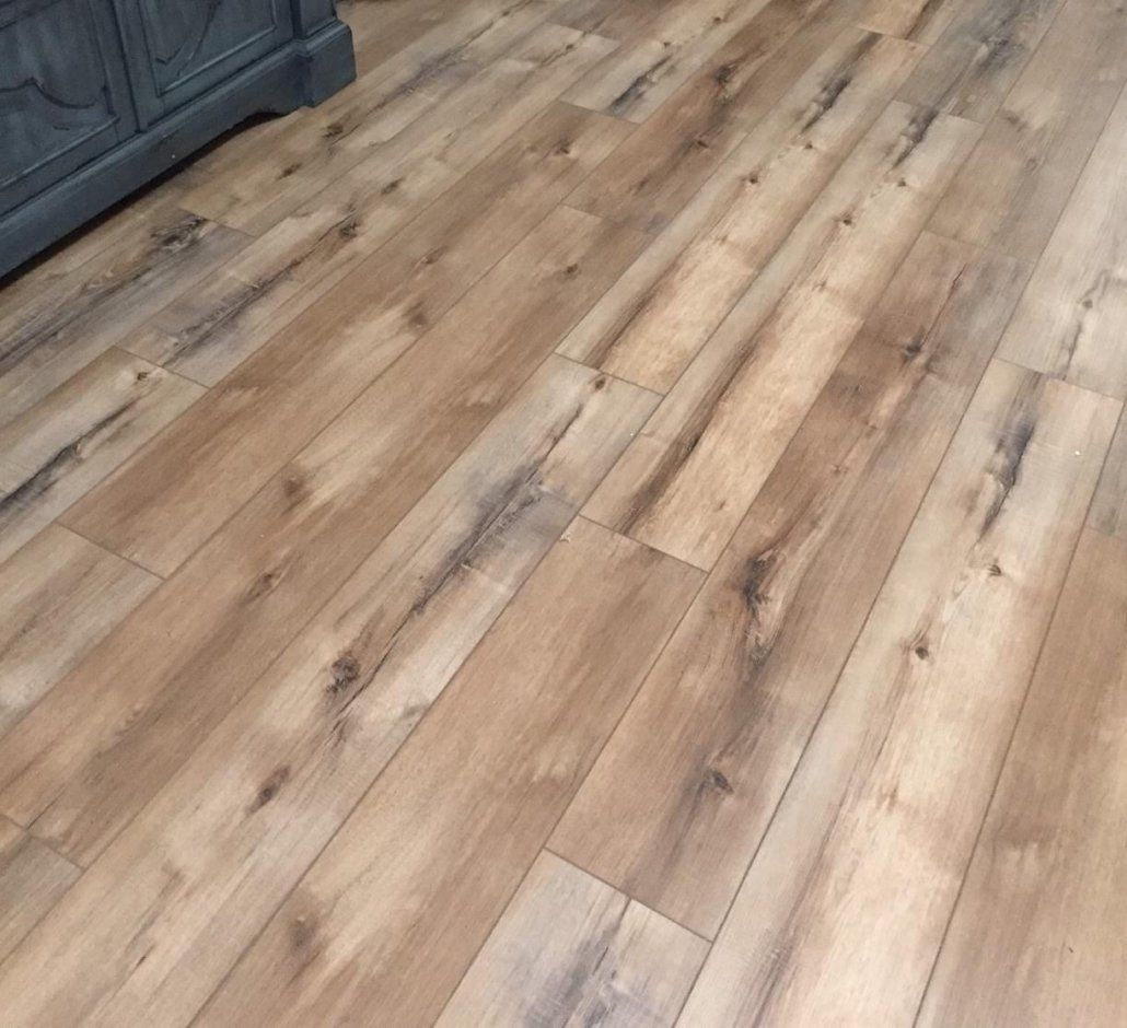 A close up of a wooden floor with a dresser in the background.
