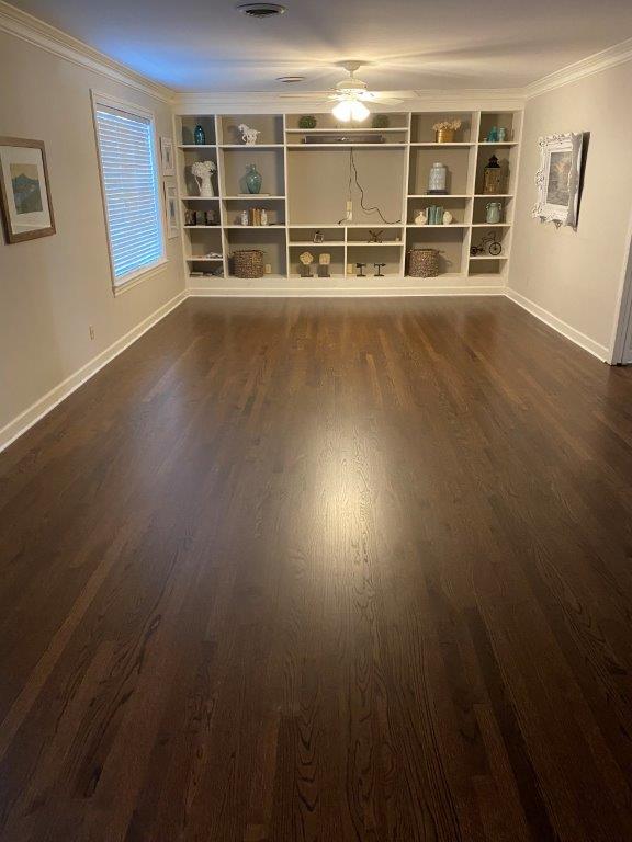 A large empty room with hardwood floors and shelves.
