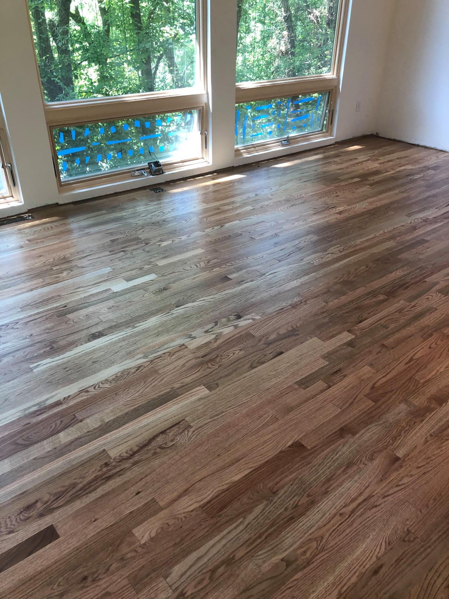 A room with a wooden floor and two windows.