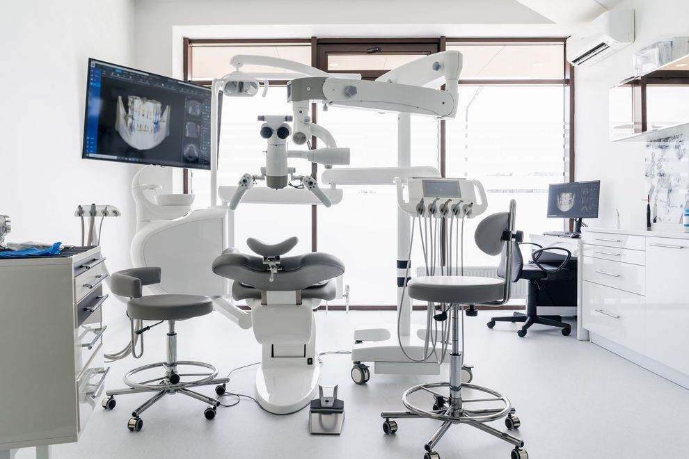 Modern dental clinic with chair, monitors, and advanced equipment in a bright white room Modern dental clinic with chair, monitors, and advanced equipment in a bright white room