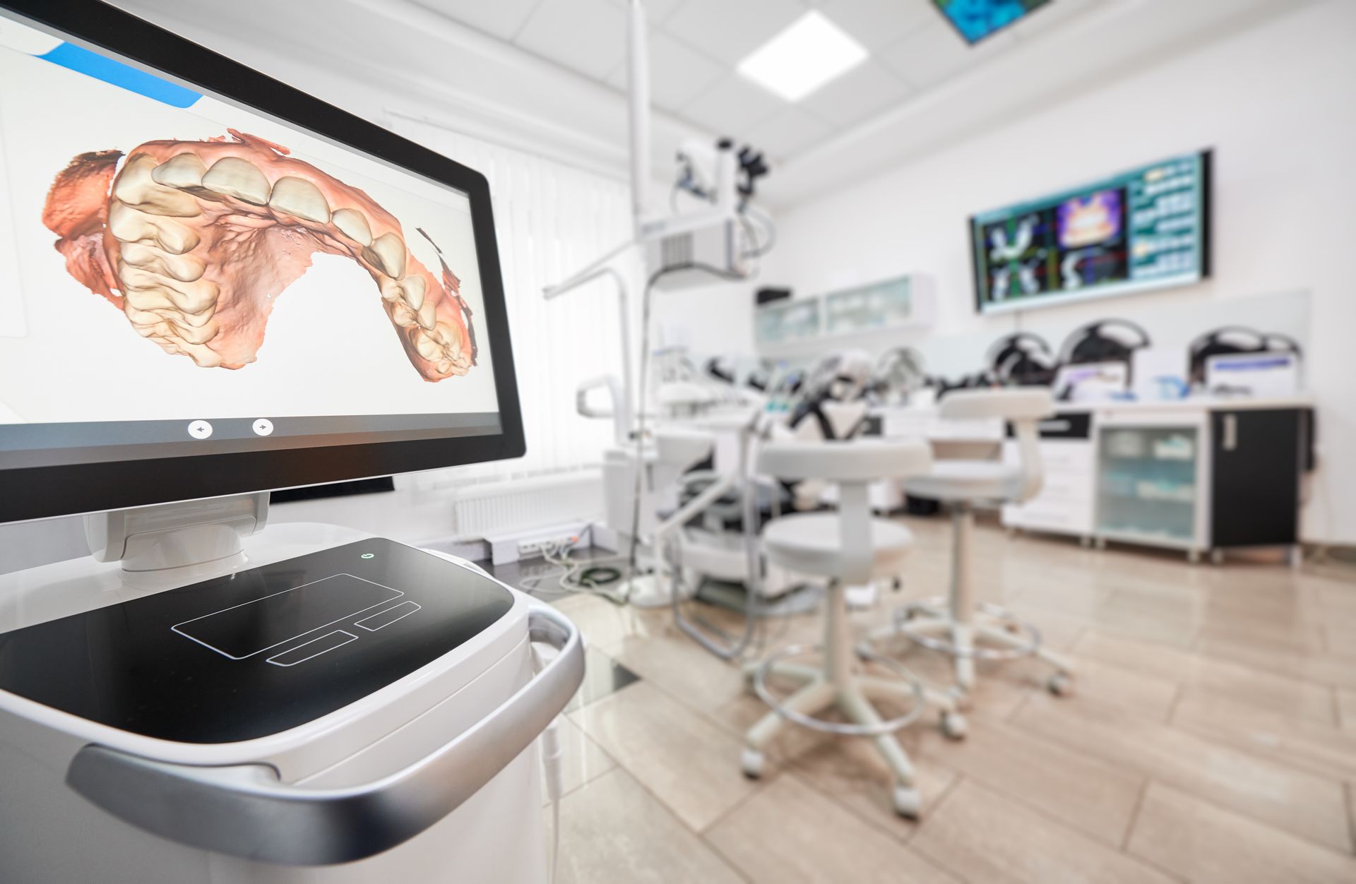 Modern dental clinic with a 3D jaw scan displayed on a monitor and treatment chairs in the background Modern dental clinic with a 3D jaw scan displayed on a monitor and treatment chairs in the background