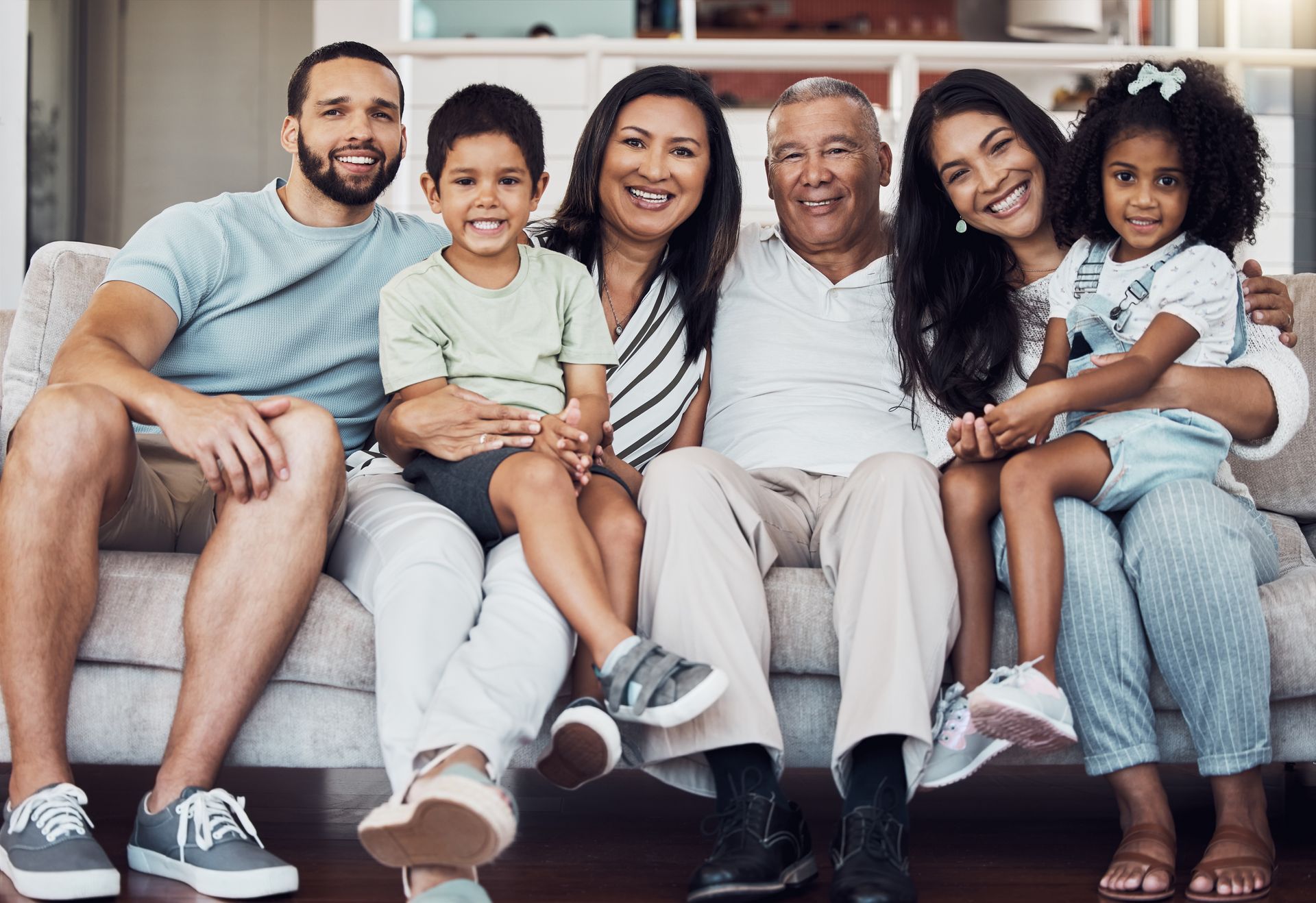 Family lying in bed with a smiling child between two adults, stretching their arms up. Family lying in bed with a smiling child between two adults, stretching their arms up.
