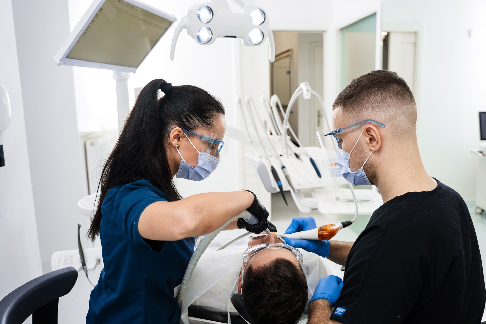 Dentist and assistant treating a patient in a bright modern dental clinic
