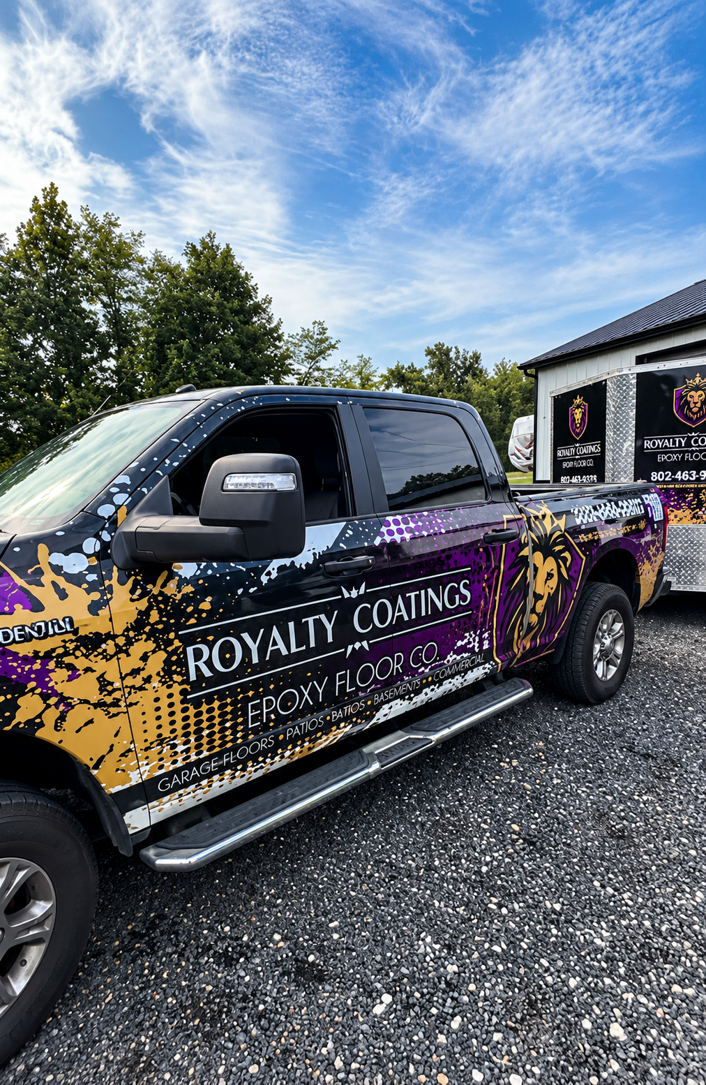 Branded black pickup truck with purple and gold graphics parked on gravel under a blue sky