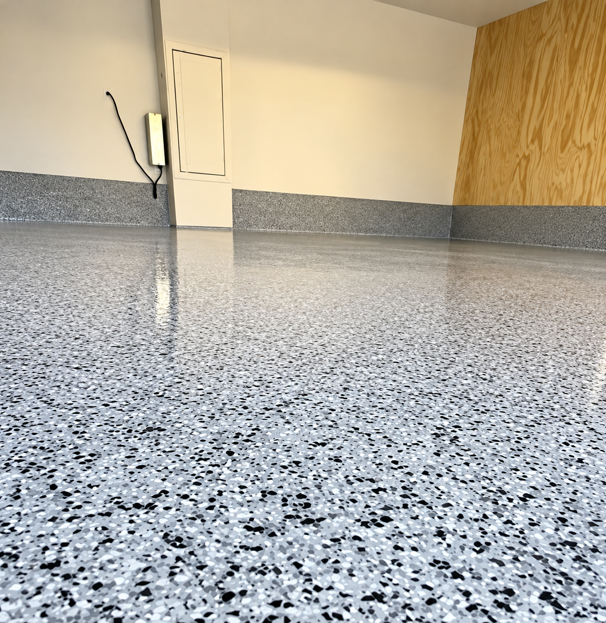 Speckled epoxy garage floor with gray wall trim and wood paneling in the corner