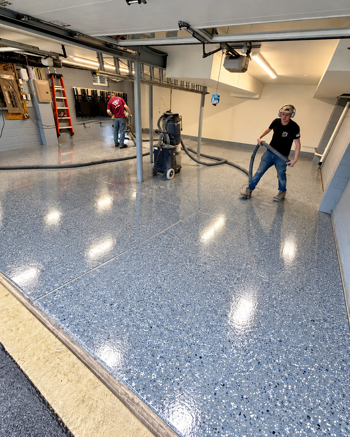 Workers installing a blue epoxy floor in a garage with tools and equipment nearby