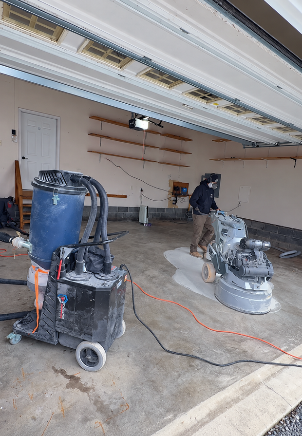 Garage with two floor buffers, extension cords, and shelves, suggesting ongoing floor refinishing work