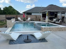 Backyard pool with lounge chairs, umbrella, and a covered patio under a cloudy sky