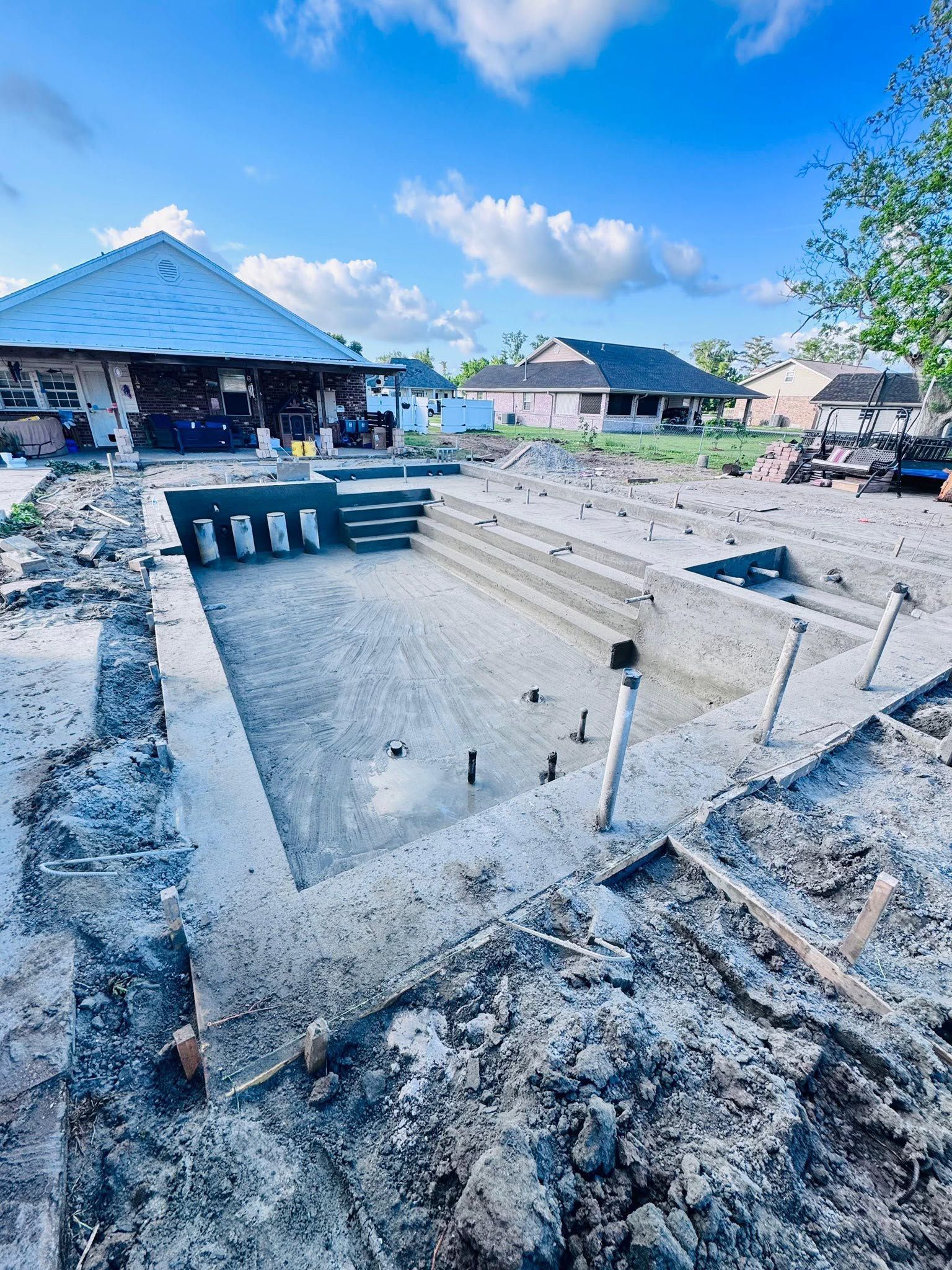 Concrete foundation under construction beside beachside houses and blue sky
