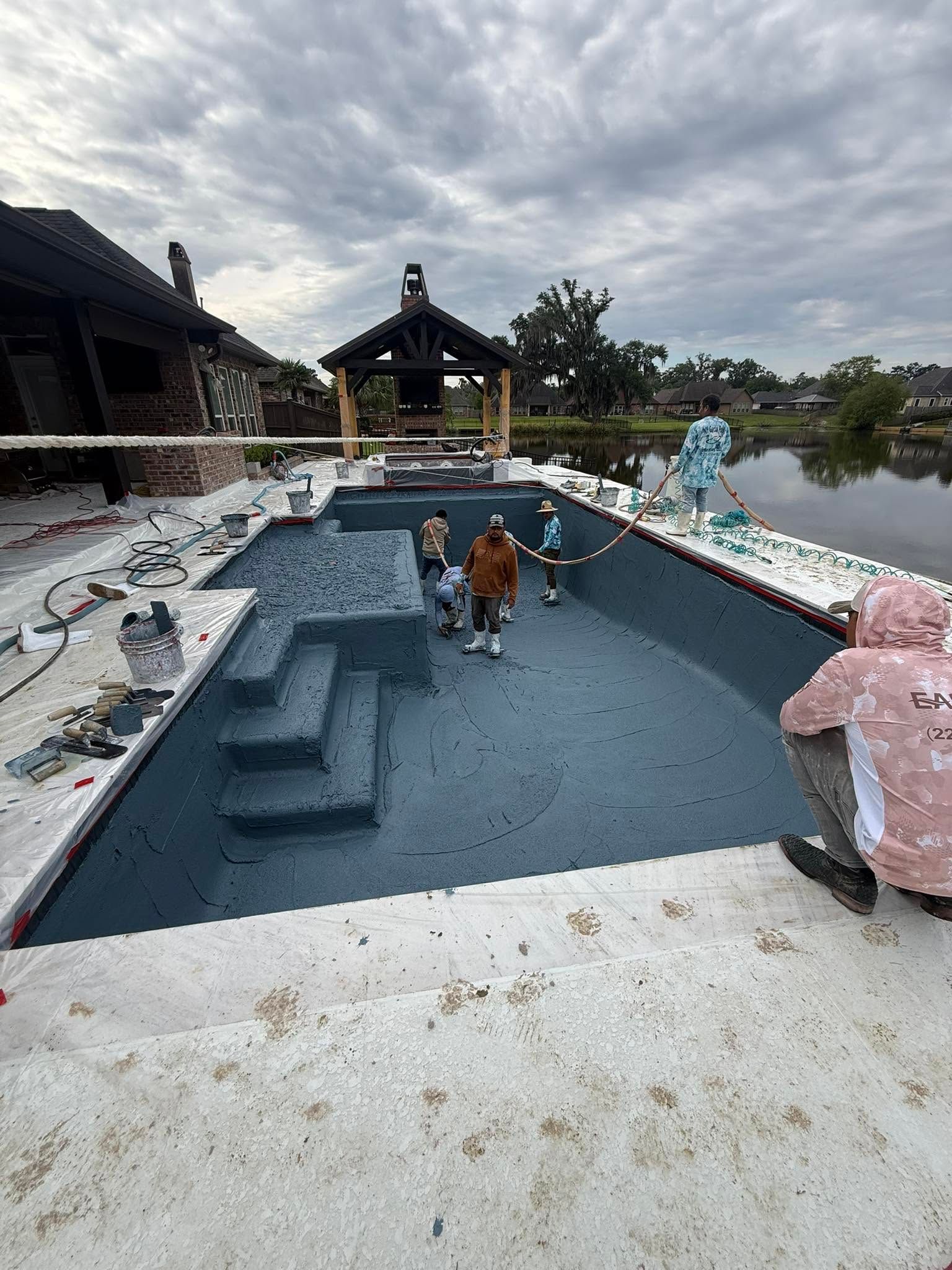Workers cleaning a blue-roofed pool with pink and blue decorative figures in a resort courtyard