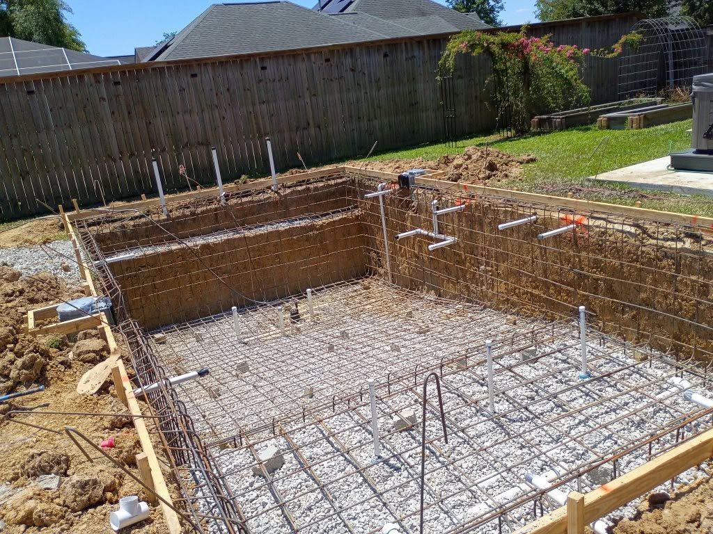 Excavated backyard foundation with steel rebar and wooden formwork for a new concrete pour