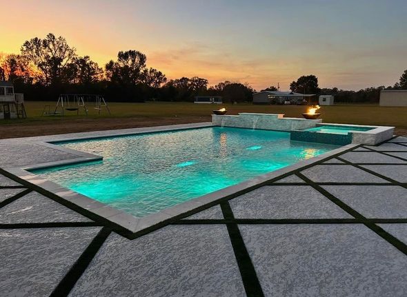 Modern backyard pool at dusk with turquoise water and geometric stone patio tiles