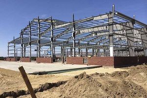A large metal structure is being built in the middle of a dirt field.