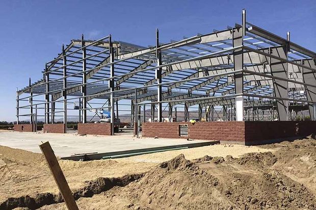 A large metal structure is being built in the middle of a field.