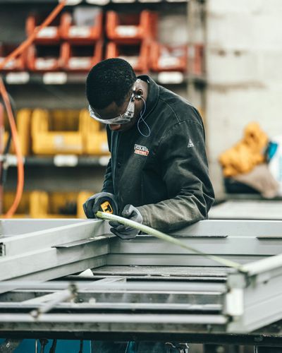 A man is measuring a piece of metal with a tape measure.
