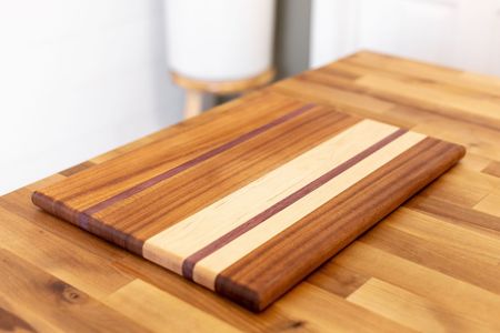 Wooden cutting board with striped inlay on a kitchen countertop