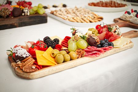 Gourmet charcuterie board with cheeses, fruit, nuts, and crackers on a white tablecloth