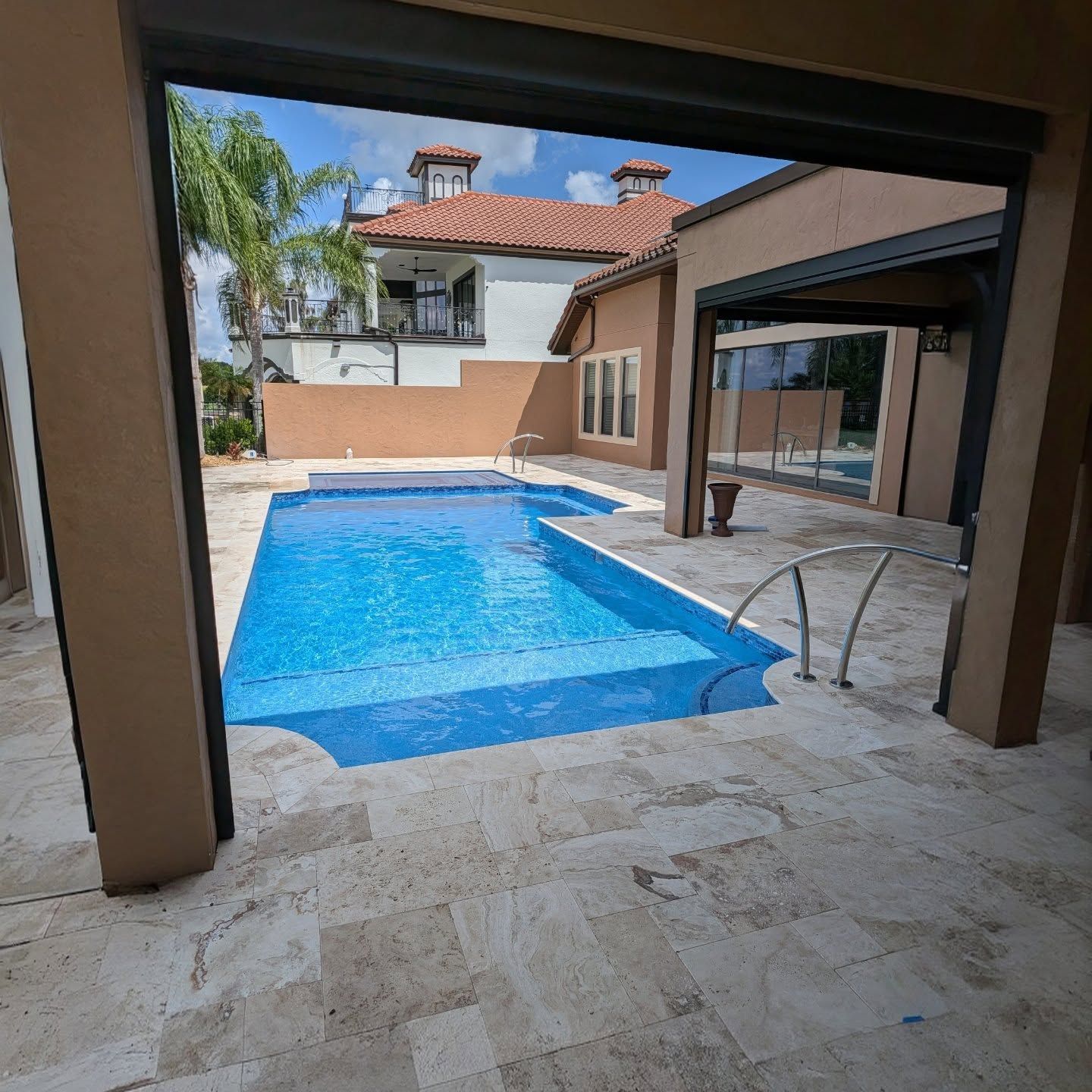 Screened backyard pool with spa and paver patio in sunlight