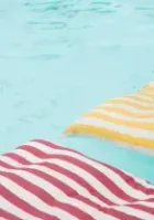 Striped red and yellow pool floats on turquoise water