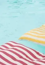 Striped red and yellow pool floats on turquoise water