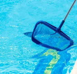 Pool skimmer net in blue water beside the pool edge
