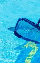 Pool skimmer net in blue water beside the pool edge