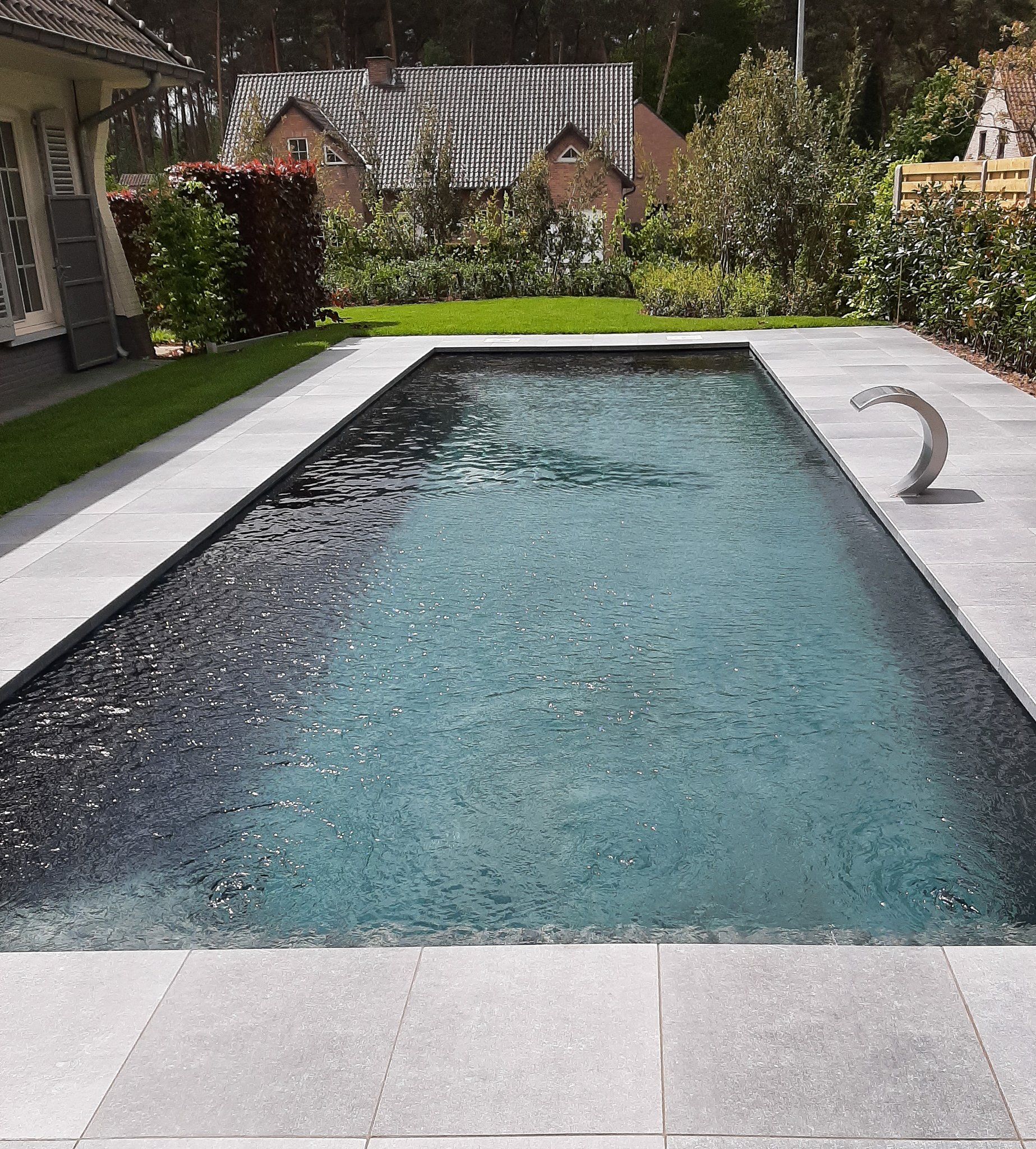 Een groot zwembad in een achtertuin met een huis op de achtergrond
