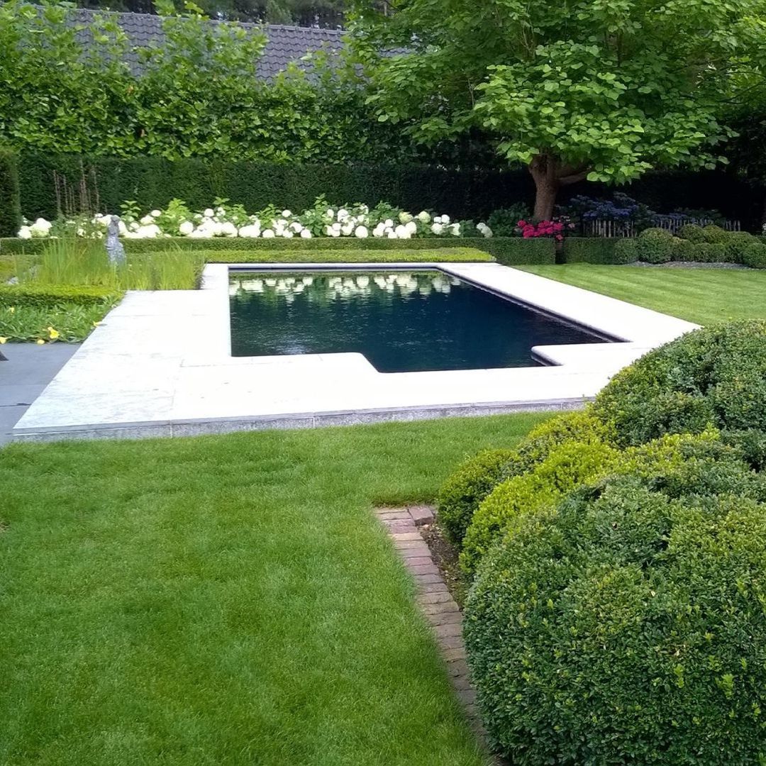 Er is een groot zwembad in het midden van een weelderige groene tuin.