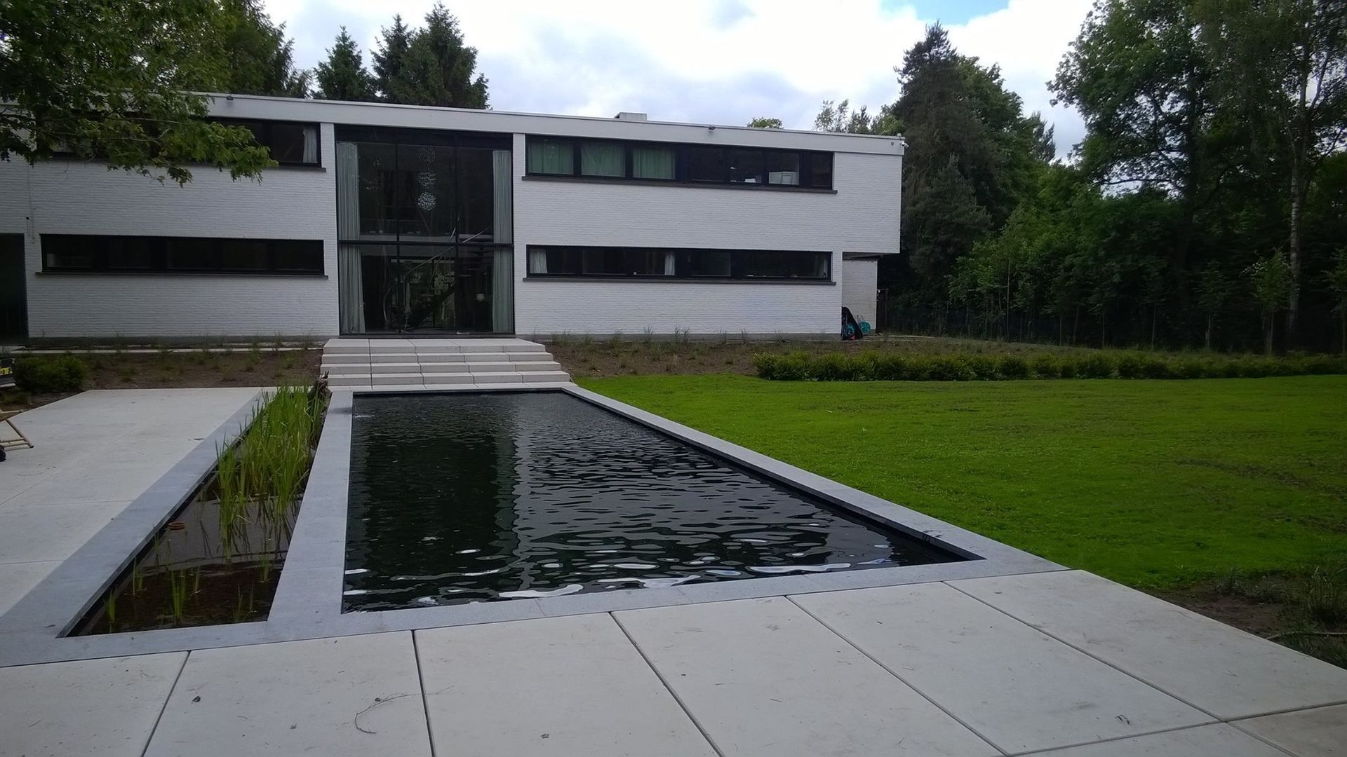 Een groot wit gebouw met een groot zwembad ervoor