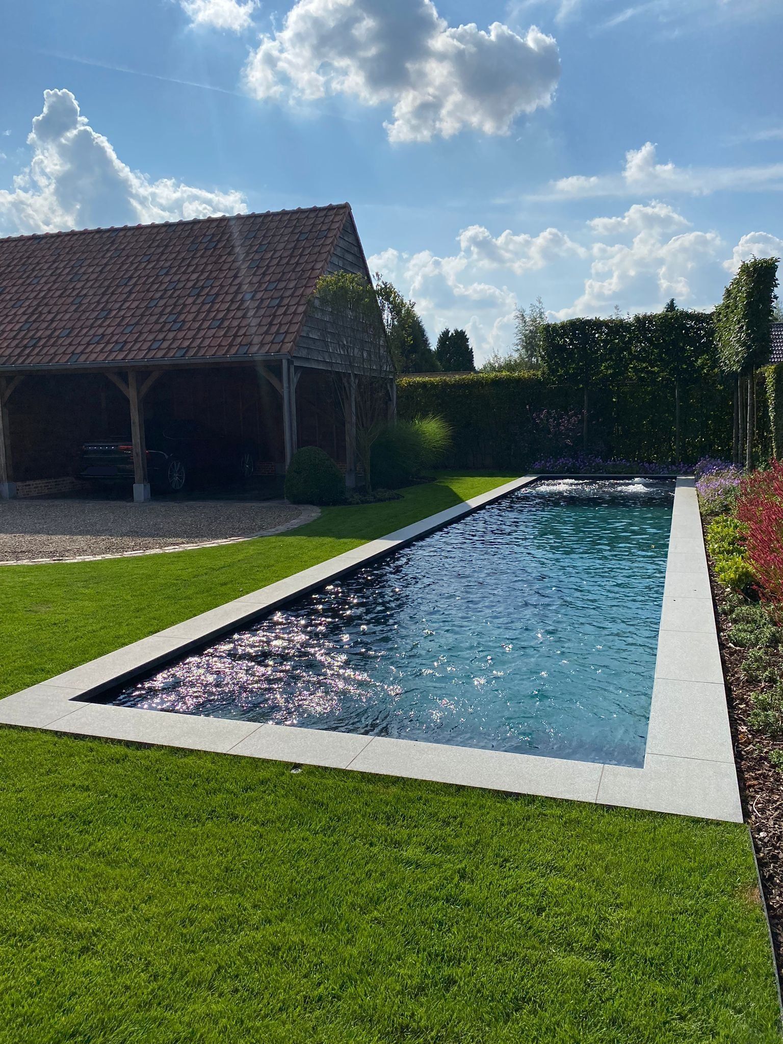 Er is een groot zwembad in het midden van een weelderige groene tuin.